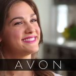 A woman smiles for the camera with the word avon in front of her.