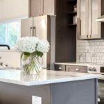 A kitchen with white cabinets and a vase of flowers.